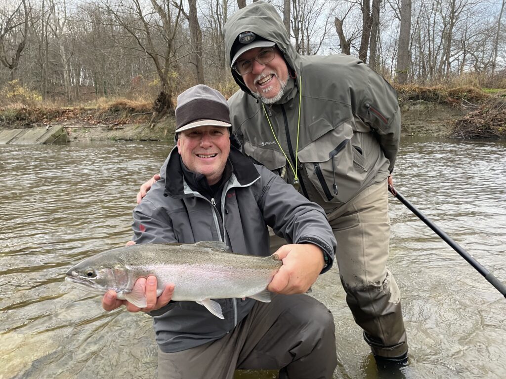 two guys with a fish on a stream