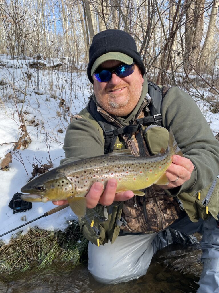 fisherman holding trout with snow in background