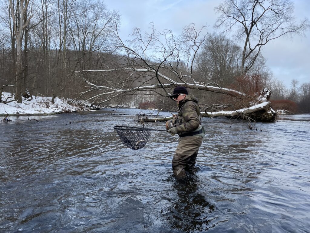 man standing in a river with snow