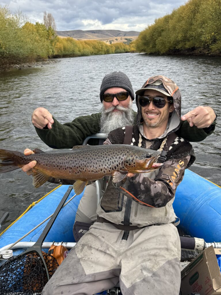 two men on a river holding a trout