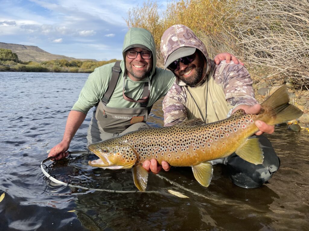 two men holding fish in a river