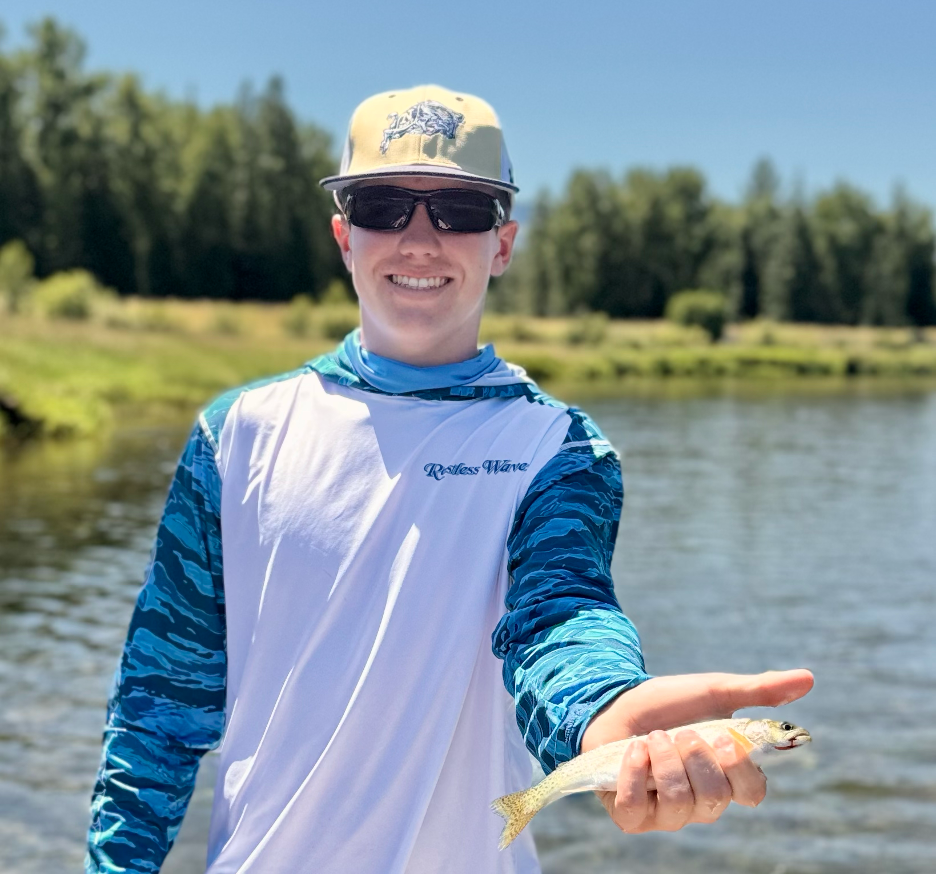 young man holding a cutthroat trout.