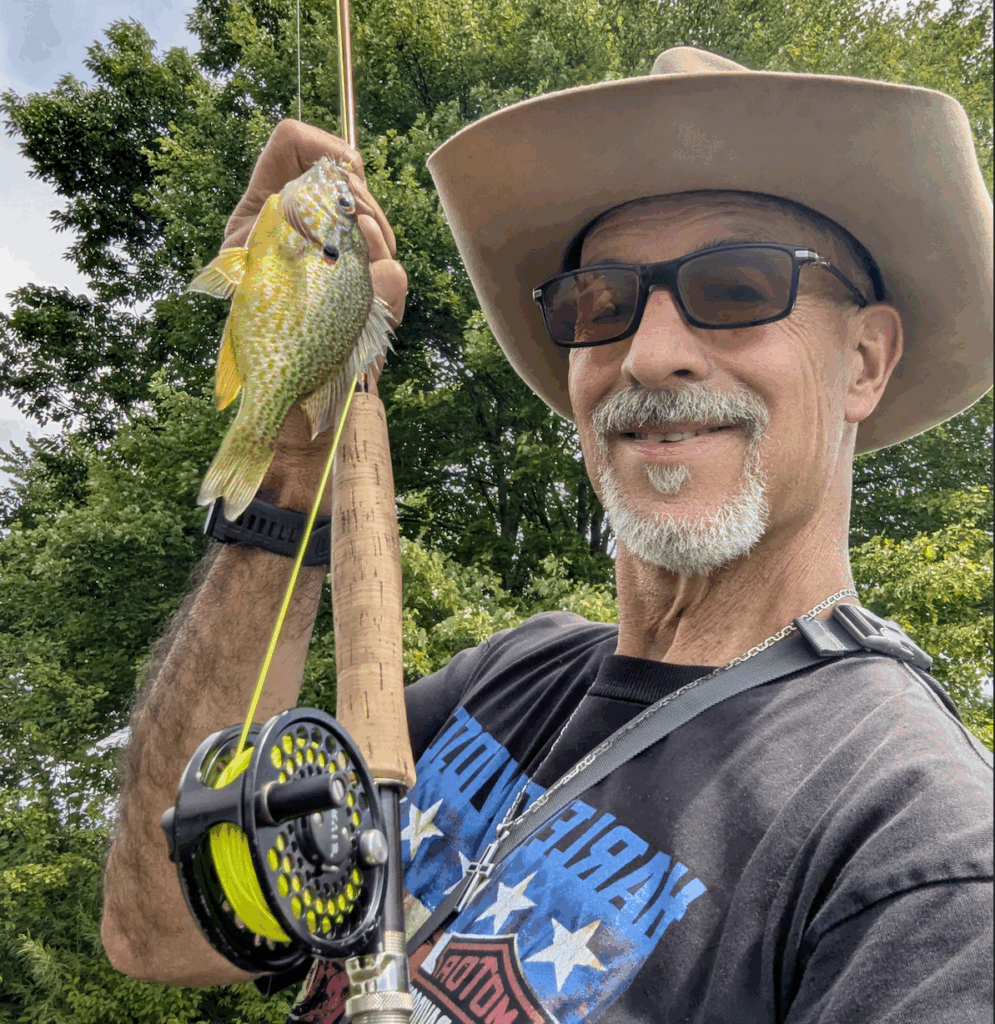 man holding a panfish and fly rod